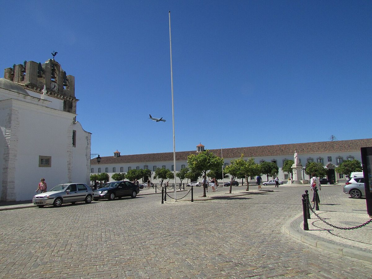 Largo da Se in Faro's walled old town with an aircraft on approach to the airport overhead