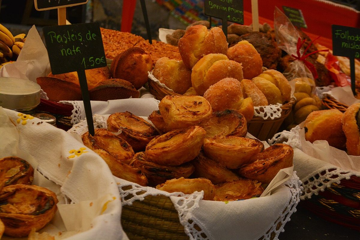 A tray of freshly baked pastéis de nata on a Portuguese bakery counter with the price marked in euros